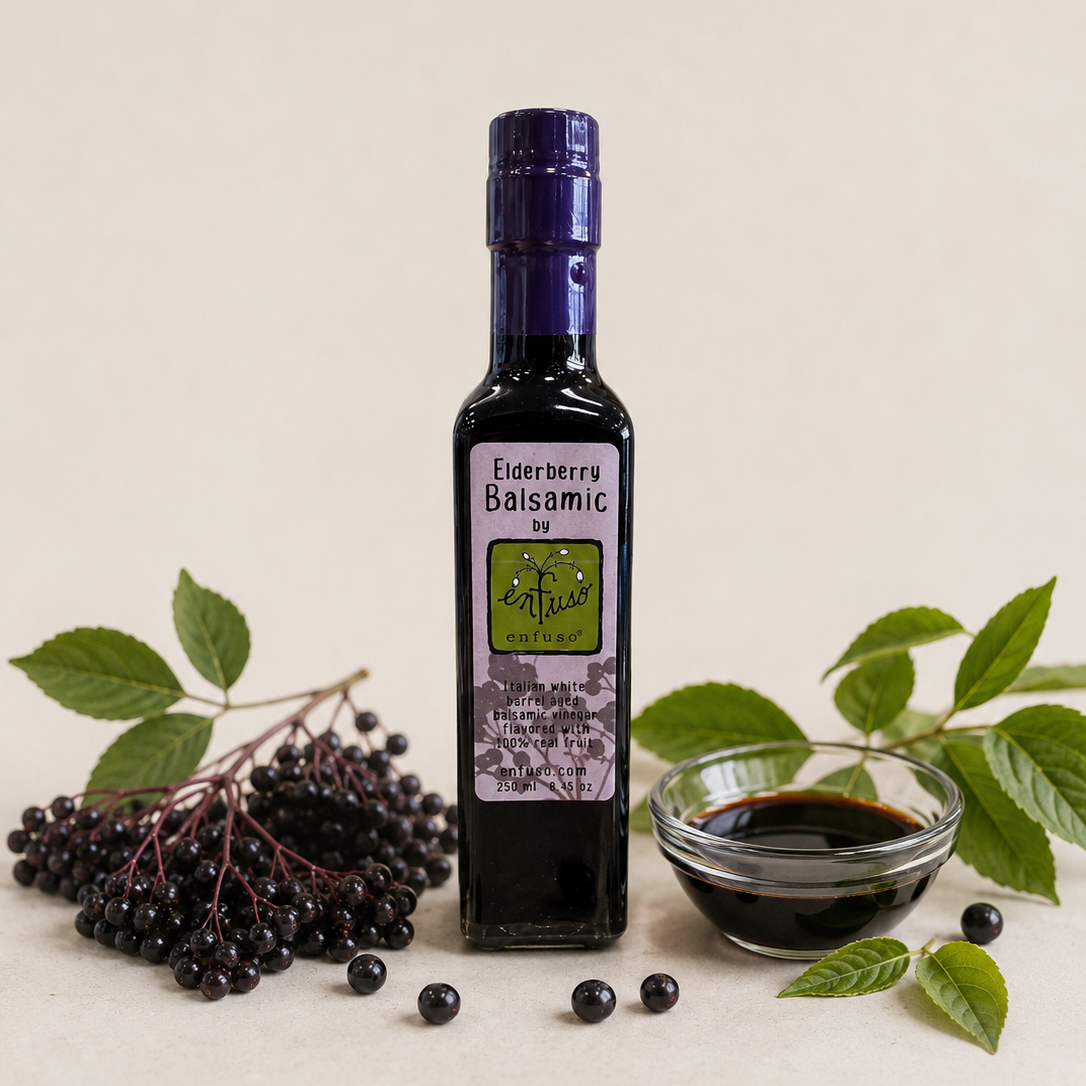 Bottle of Elderberry Balsamic with a small bowl of the product and elderberries on a light background