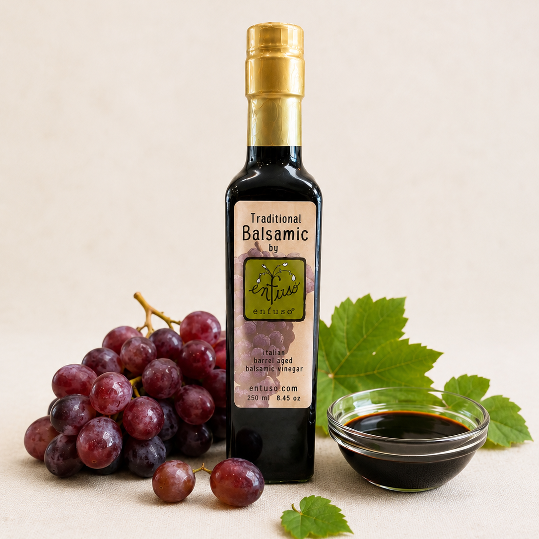 Bottle of balsamic vinegar with grapes and a leaf on a beige background