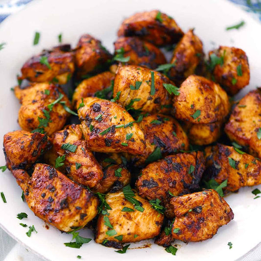 Grilled chicken pieces with herbs on a white plate