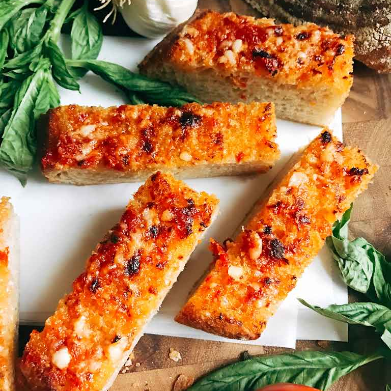 Crusty bread slices with tomato and basil on a wooden board