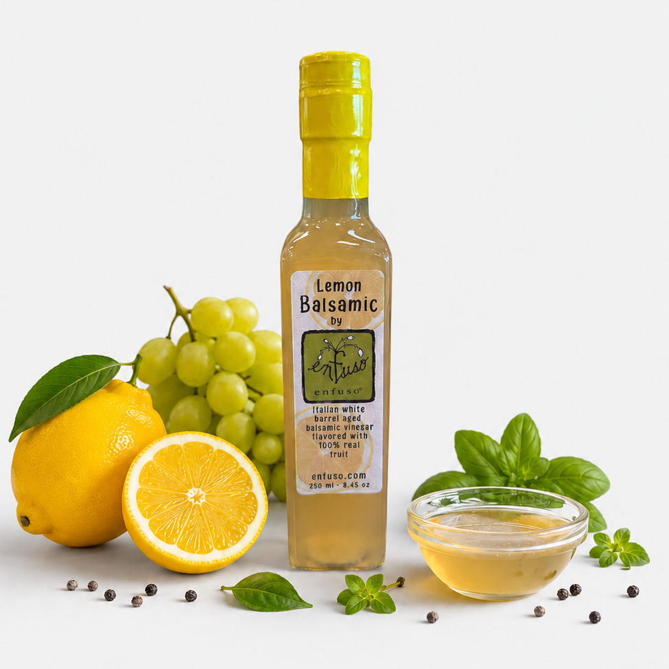 Bottle of Lemon Balsamic vinegar with lemons, grapes, and basil on a white background