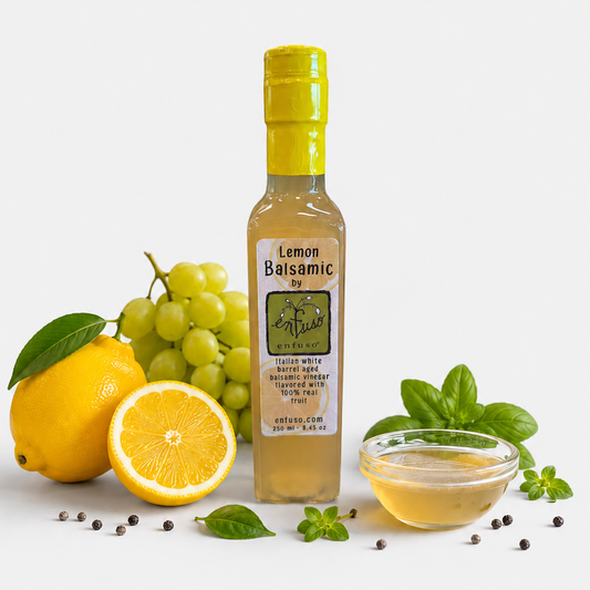 Bottle of Lemon Balsamic vinegar with lemons, grapes, and basil on a white background