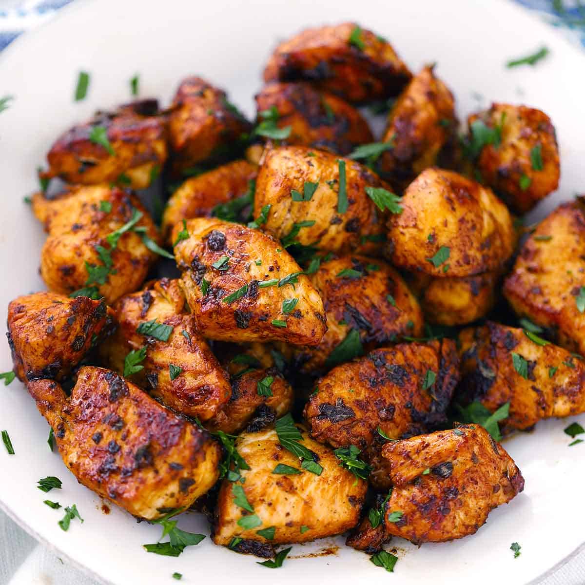 Grilled chicken pieces with herbs on a white plate