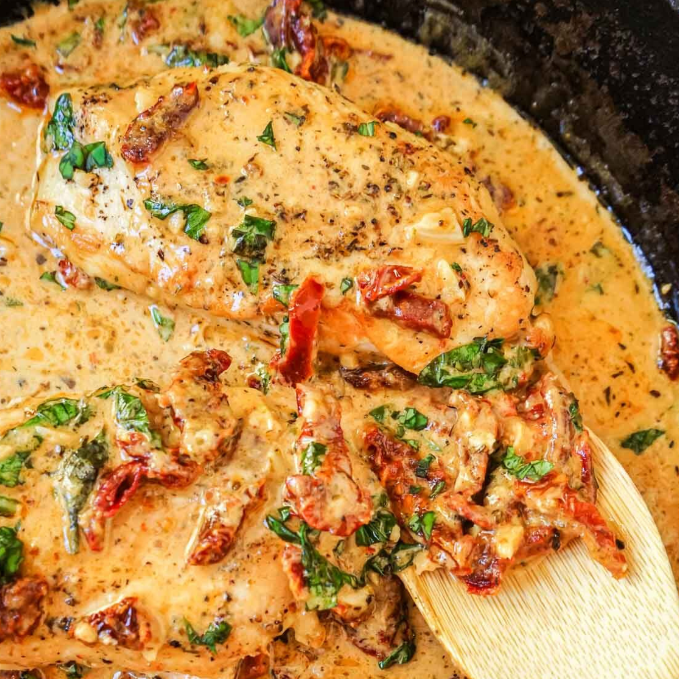 Creamy chicken dish with sun-dried tomatoes and spinach in a skillet.