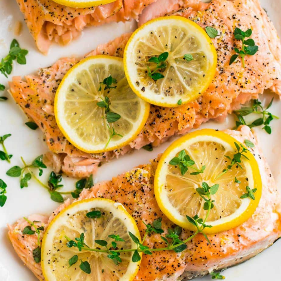 Salmon fillets with lemon slices and thyme on a white plate